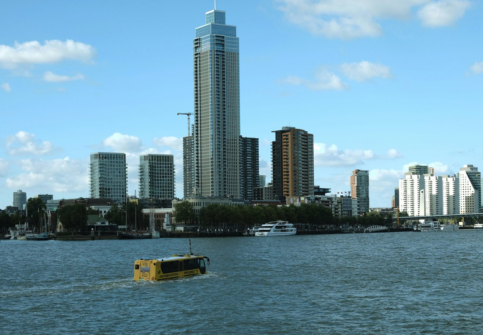 a yellow boat in a body of water with a city in the background